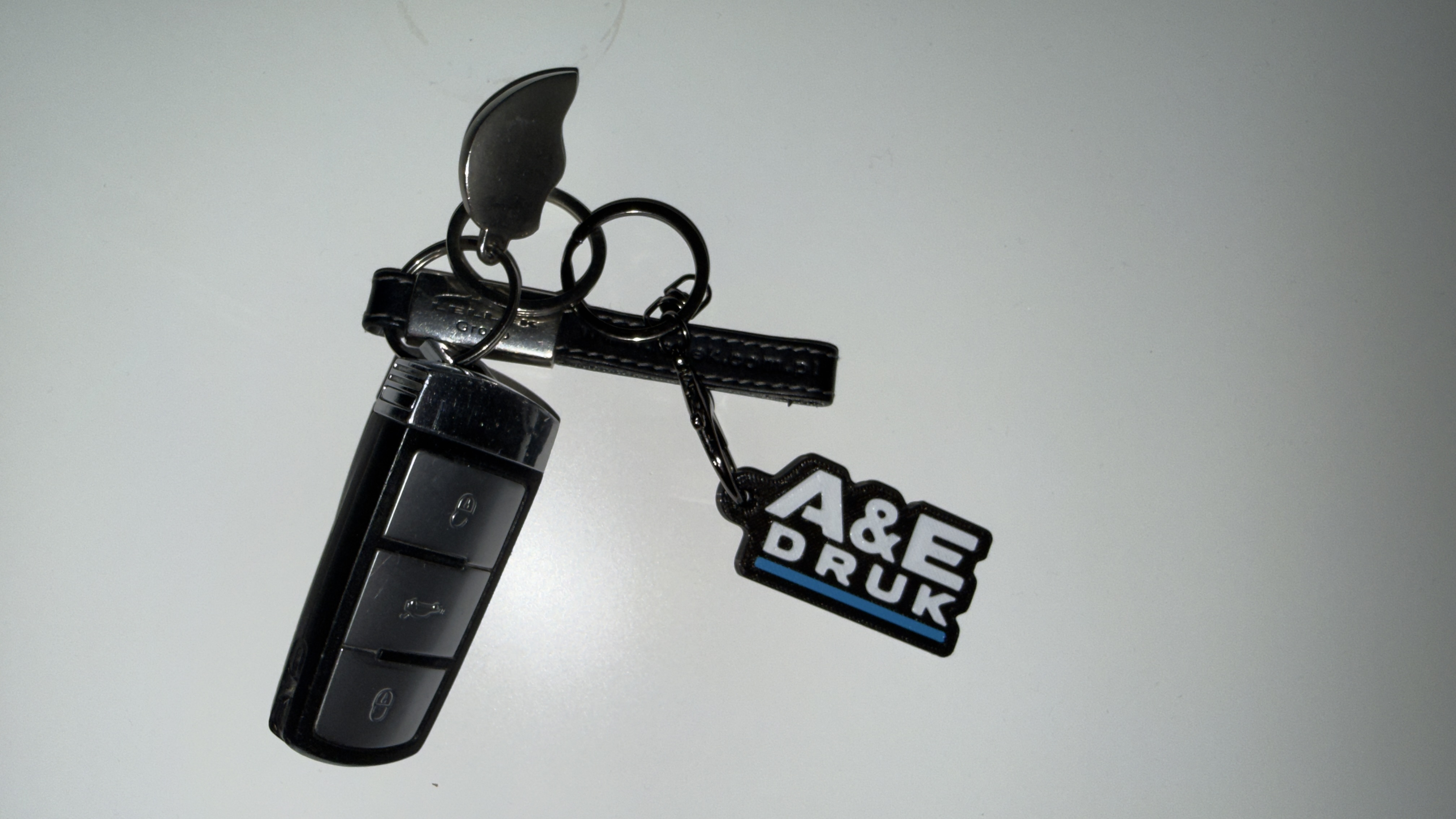 Brelok z logo A&E Druk przypięty do kluczy samochodowych
